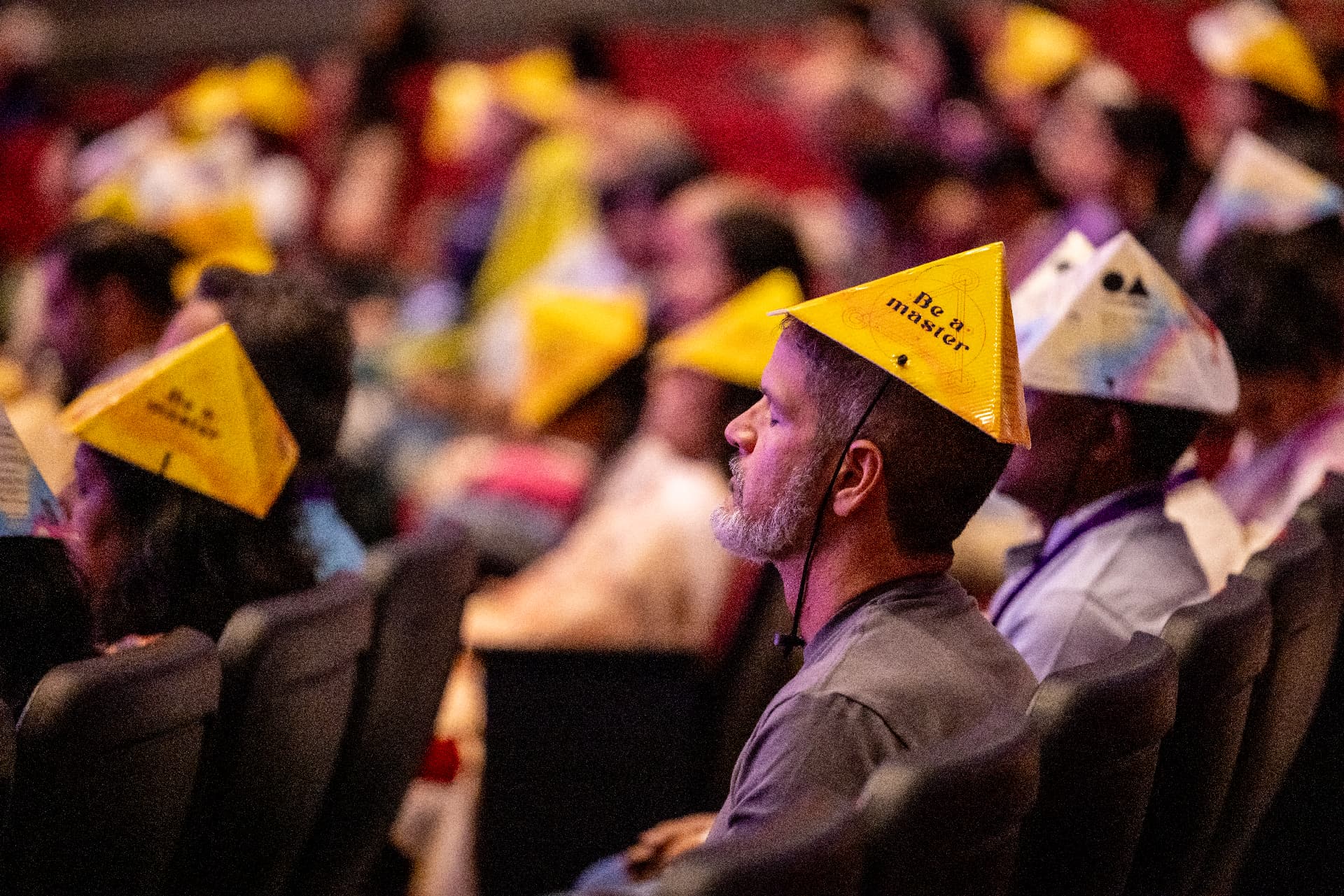 People meditating with eyes closed under pyramid caps